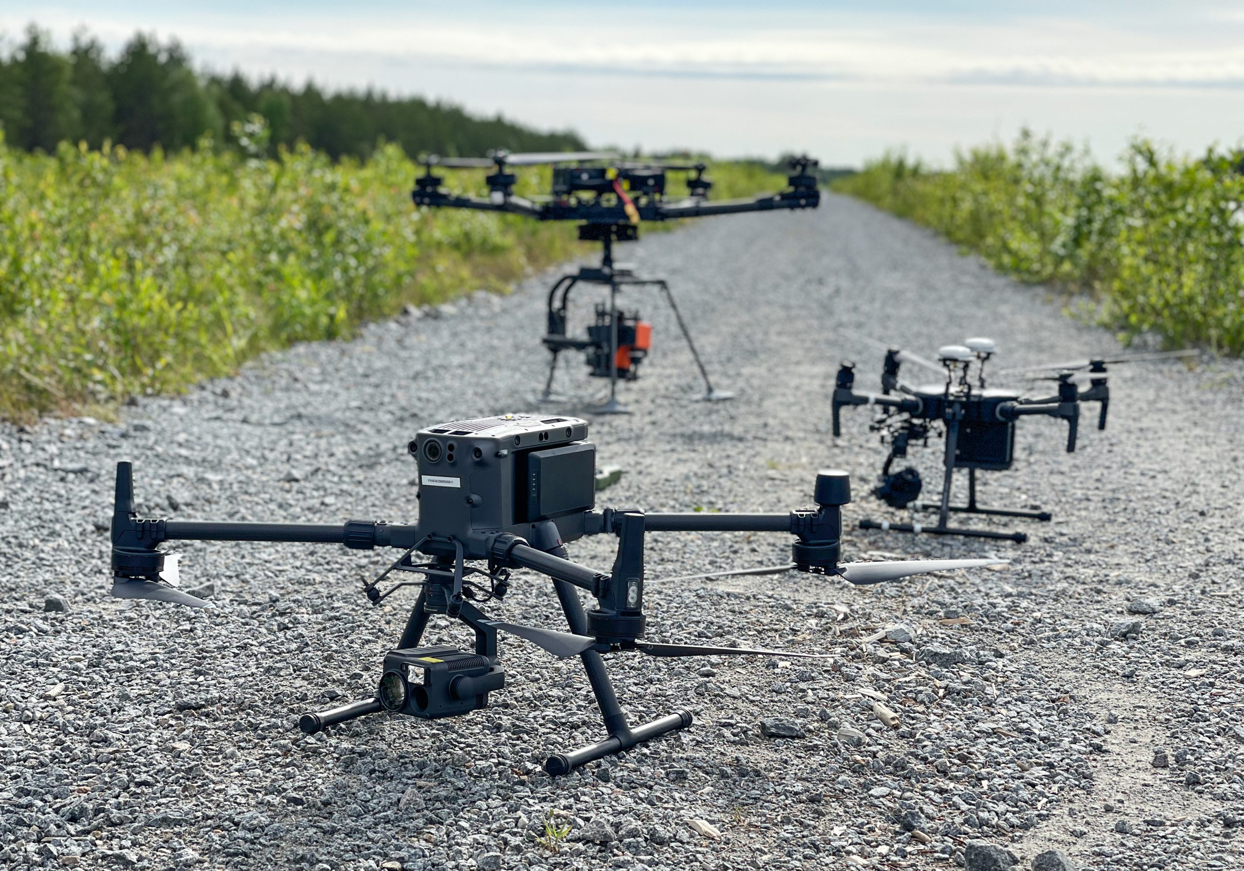 Three drones on a gravel road